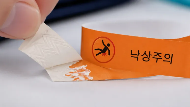 손가락으로 낙상주의 밴드의 이형지를 떼어내는 모습